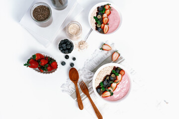 Presented by fruits putting yogurt toppings with strawberry, berry, oats, raisins and chia seed decorated by peppermint in white blow. Pink background. Set of healthy dairy product choice. Pecuniary.