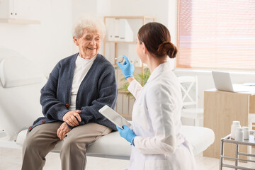 Obraz premium Senior woman receiving hearing aid from doctor in clinic