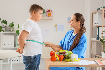 Female nutritionist measuring overweight boy's belly in clinic. Diet concept