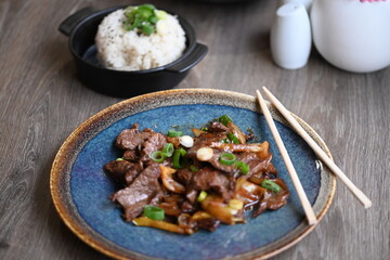 A close-up shot of a traditional Korean dish, Bulgogi, served in a rustic restaurant setting.