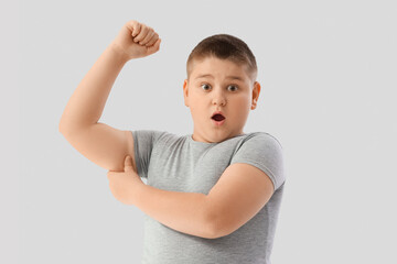 Shocked overweight boy with chubby arms on light background. Diet concept