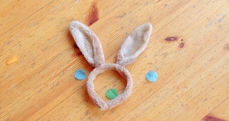 A charming headband with cute bunny ears is placed on rustic wood, surrounded by colorful circles, evoking joy for all who see it