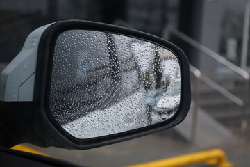 Detail of car mirror wet by raindrops.