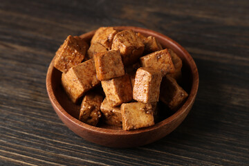 Bowl with pieces of fried tofu cheese on wooden background