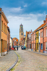 Fototapeta premium Bruges cityscape, narrow cobblestone street, colorful buildings and houses in Brugge city historical centre, Bruges old town quarter, St. Salvator's Cathedral Roman Catholic church tower, Belgium
