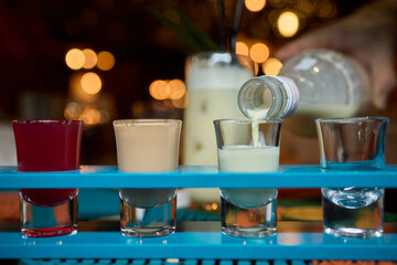 Brightly colored shot glasses filled with a delicious pouring drink that enhances fun
