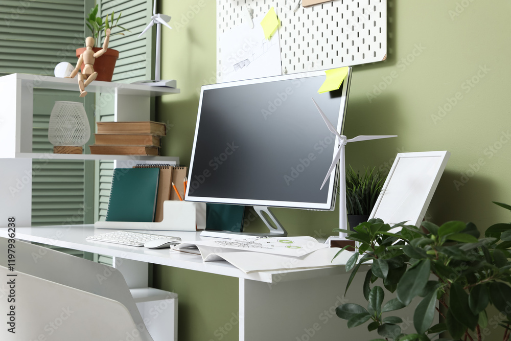 Poster engineer's workplace with blank computer monitor and wind turbine models in office
