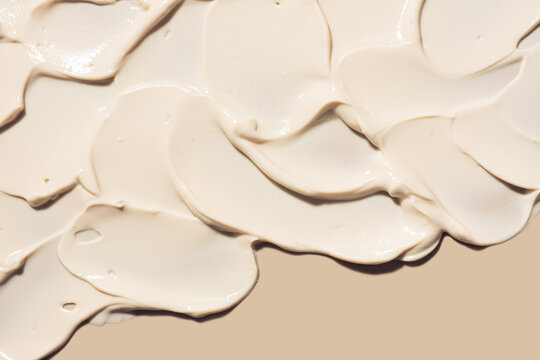 Cosmetic milky beige cream balm thick nourishing or mask texture smudge on beige background