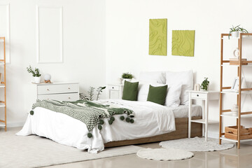 Interior of stylish bedroom with cozy bed, bedside table and beautiful paintings