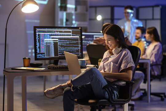 Female programmer working with laptop in office at night