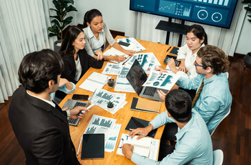 Diverse group of business analyst team analyzing financial data report. Finance data analysis chart and graph dashboard show on TV screen in meeting room for strategic marketing planning. Habiliment