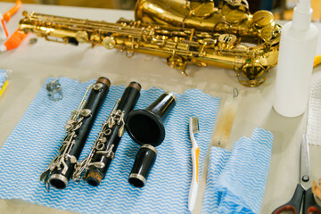 Repairman cleaning disassembled clarinet with saxophone on table