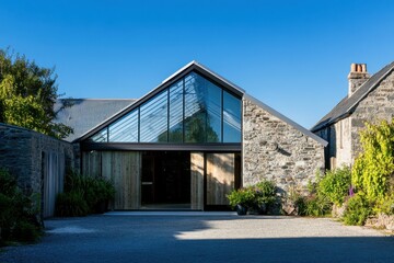 Fototapeta premium Modern architectural design merges with rustic charm in a spacious stone house surrounded by vibrant greenery set against a clear blue sky
