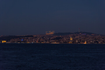 Istanbul city lights across dark water at night, Bosphorus skyline view, Turkey