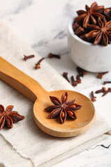 Wooden spoon and bowl with anise stars on white background