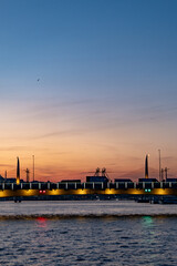 panoramic photograph capturing Istanbul's historic peninsula bathed in a crimson sunset glow. The city's iconic skyline silhouettes against the vibrant evening sky, highlighting its rich architectural