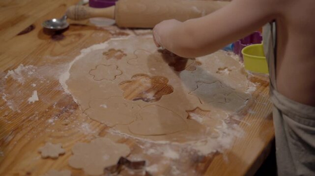 Baking holiday cookies with colorful cutters and a wooden rolling pin