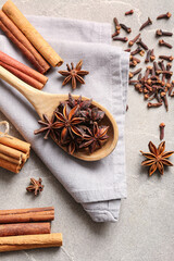 Wooden spoon with anise stars, cinnamon and cloves on grey background