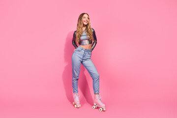 Stylish young woman posing with pink roller skates against a vibrant pink backdrop