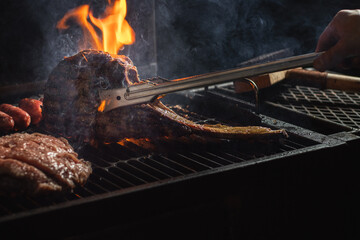 Beef steak on the grill with smoke and flames.