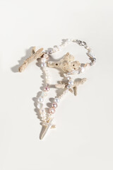 Necklace of various natural baroque pearl beads and marine corals on white background. Pearl cross