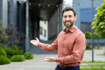 Successful man invites to work in a new team. Businessman looks at the camera and holds hands to...