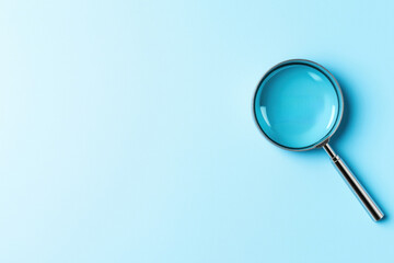 Magnifying glass on light blue background. Business concept. Focus on details. Illustrates inspection, investigation. Ideal for stock photo graphic design project. Examining financial data documents.