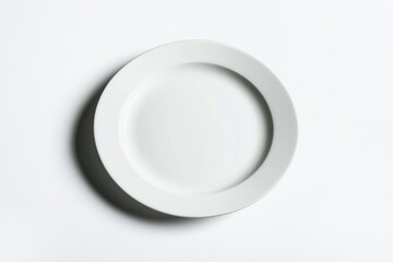 Empty white plate on white background. Top view. Clean, simple tableware. Ideal for new dishware designs. Modern kitchenware. Simple, stylish. Empty plate ready for food. Restaurant home setting.