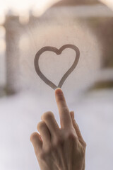 Heart on a glass of a window and a finger , tender scene, touching moment