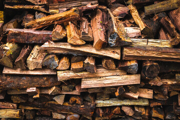 Close-up of stacked firewood: textured pile of chopped logs for rustic ambiance