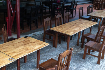Empty outdoor cafe with wooden tables and chairs in evening light
