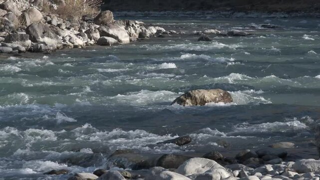 Seething water quickly flows over the stones. Mountain river in autumn, slow motion