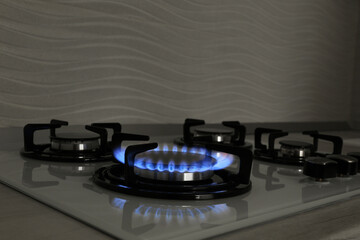 Modern gas cooktop with burning blue flame in kitchen