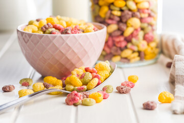 Colorful breakfast cereals in the shape of various fruit in bowl on white table.