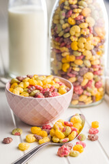 Colorful breakfast cereals in the shape of various fruit in bowl on white table.