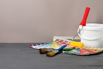 Different painter's tools on grey wooden table, space for text. Decorating and design