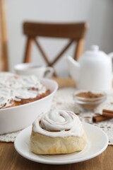 Delicious frosted cinnamon rolls on wooden table indoors, closeup