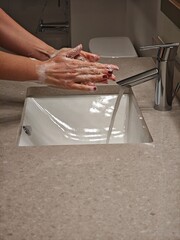 Hands cleansing with soap at a modern sink in a well-lit bathroom during daytime