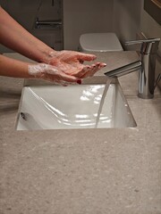 Washing hands at a modern sink in a stylish bathroom with sleek fixtures and soothing colors