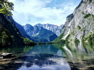 A peaceful lake nestled among the Bavarian mountains, surrounded by lush green trees and vibrant summer colors.
