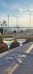Obraz premium two glasses of white wine on a table in a cafe by the sea. aperitif before dinner. resort cafe on the seashore. beauty in nature and dinner at sunset