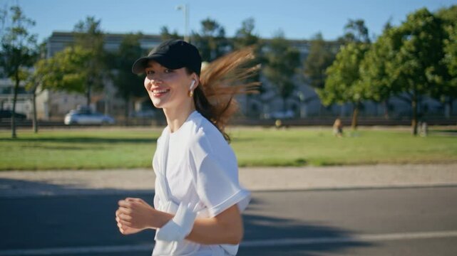 Happy girl jogging road wearing wireless earbuds closeup. Smiling woman running