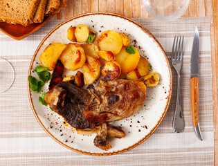 Grilled lamb thigh and some potatoes served in a plate with other table appointments