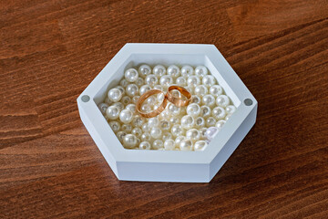 A white box filled with pearls on top of a wooden table