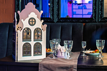 A table set for a dinner party with a model of a house on it