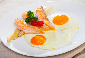 Delicious breakfast. Over easy fried eggs with salmon steaks and baked white asparagus