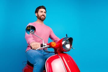 Confident man in casual attire riding a vintage red scooter against a vibrant blue background