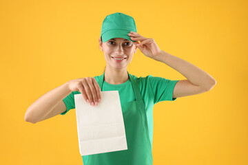 Fast-food worker with paper bag on orange background