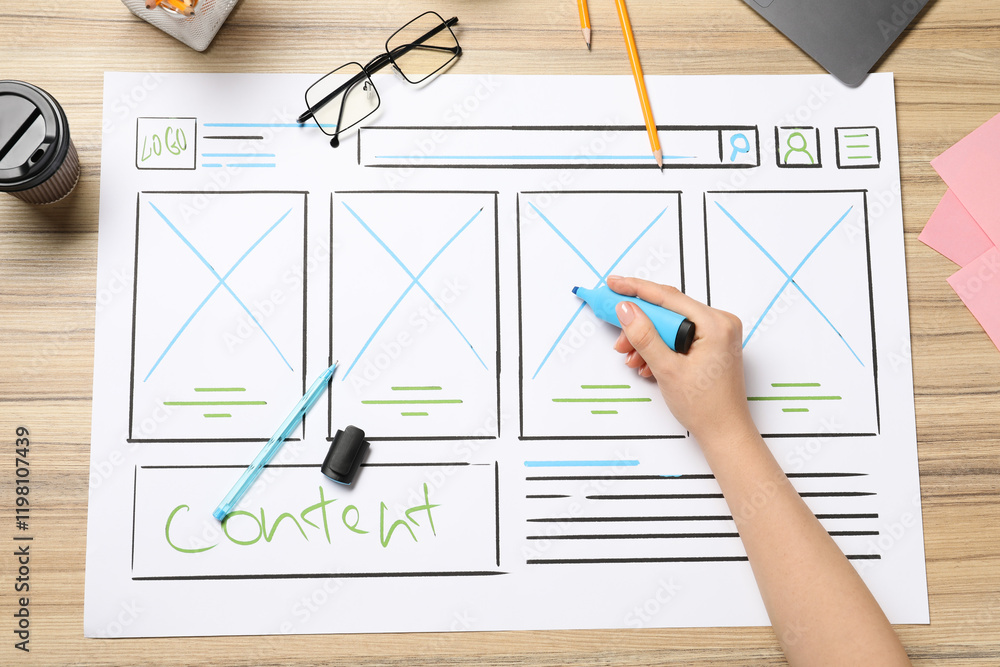 Aufkleber website designer creating wireframe on paper with highlighter at wooden table, top view