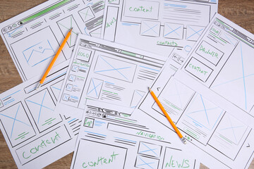 Developing UI design. Sketches of website wireframes and pencils on wooden table, top view